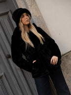 Cappotto di pelliccia nero con cappuccio.