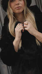 Cappotto di pelliccia nero con cappuccio.